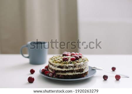 homemade cake with spinach and cream decorated with fresh cranberries on white table, diet breakfast