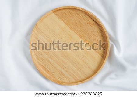 empty circle brown wooden tray placed on white Crumpled fabric. Royalty-Free Stock Photo #1920268625