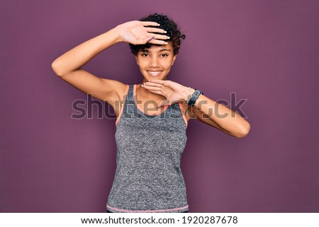 Young beautiful african american afro sportswoman doing exercise wearing sportswear Smiling cheerful playing peek a boo with hands showing face. Surprised and exited