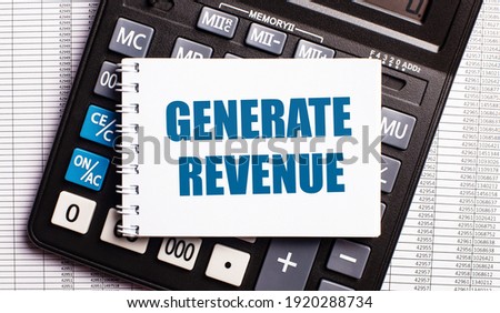 On the table are reports, a calculator and a card with the words GENERATE REVENUE on it. Business concept