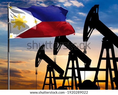 Oil rigs against the backdrop of the colorful sky and a flagpole with the flag of Philippines. The concept of oil production, minerals, development of new deposits.