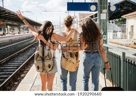 Three young beautiful female women at station to catch train for their vacation together during Coronavirus Covid-19 pandemic wearing protective face masks - Millennials have fun during the holidays Royalty-Free Stock Photo #1920290660