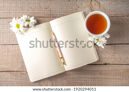 Cozy breakfast in spring or early autumn tea with bouquet of Chamomile daisy flowers and note book. Copy space, top view flat lay 