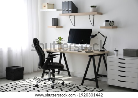 Comfortable office chair near table with modern computer Royalty-Free Stock Photo #1920301442