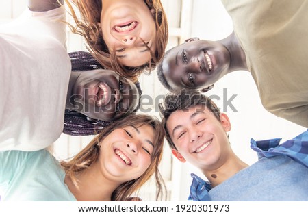 No Racism concept. Happy friends of different races smiling together embracing. Upward view from the ground, faces looking to camera. Royalty-Free Stock Photo #1920301973