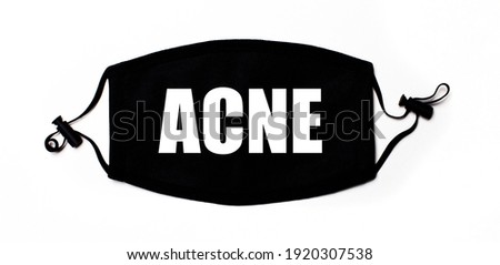 Black medical face mask on a light background with the inscription ACNE. Disease prevention. Medical concept