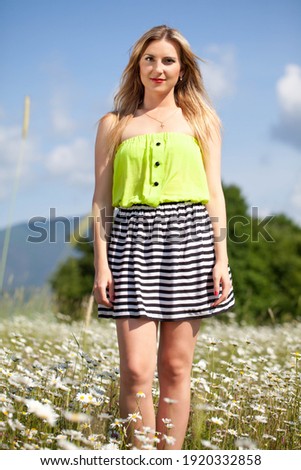 Young beautiful woman with blond hair in a daisy field. 