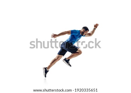 In air. Caucasian professional male athlete, runner training isolated on white studio background. Muscular, sportive man. Concept of action, motion, youth, healthy lifestyle. Copyspace for ad. Royalty-Free Stock Photo #1920335651