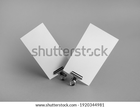 Photo of blank business cards and metal binder clips on gray background. Branding ID template.
