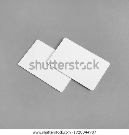 Photo of two blank white business cards on gray paper background. Branding ID template.