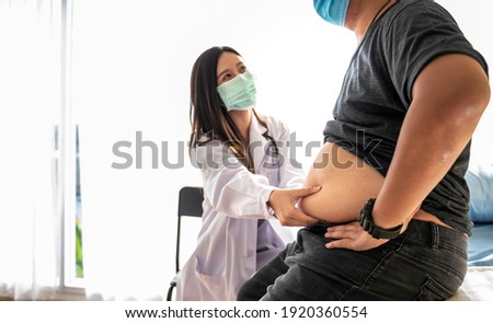 Blurred soft images of Asian woman doctor using a hand to hold the belly fat Of obese man patients, who received treatment for diabetes Caused by obesity, This picture focused on doctor's hand