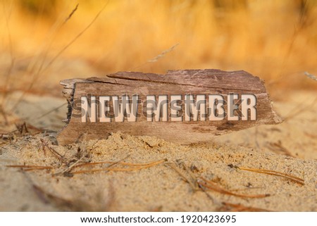 Concept, business and finance. In the sand against the background of yellow grass there is a sign with the inscription - NEW MEMBER