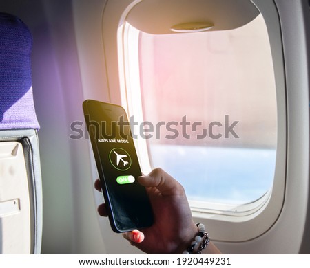 Flight mode concept Slide your finger on the screen to turn on Airplane mode, cut off the smartphone communication near the window on the plane. For the safety of the trip Royalty-Free Stock Photo #1920449231