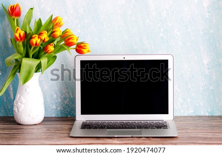 Office or home workspace with bouquet of colorful tulips on the table. Feminine workspace