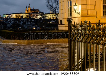 railings in the park near Charles Bridge and in the background Prague Castle in the evening in the center of Prague in winter and light reflections on the sidewalk