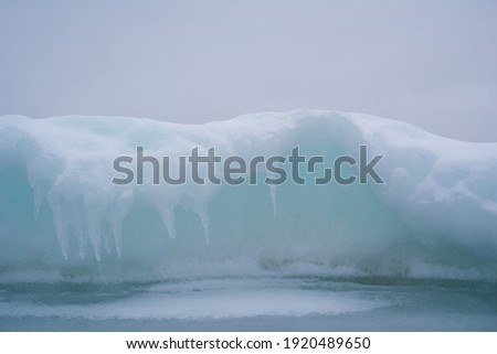 Frozen moment of wave curving over the sea ice. Aqua blue color inside the curves. 