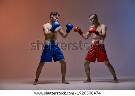 Wrestling of two fighting males boxers in red light in studio, martial arts, mixed fight concept