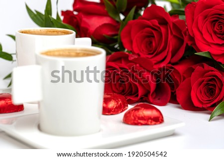 cup of coffee and a bouquet of red roses on a white table