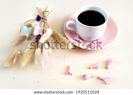 Colored dry lagurus bouquet and cup of coffee on a soft beige background. Flat lay, top view. Concept of holiday, birthday, Easter, March 8