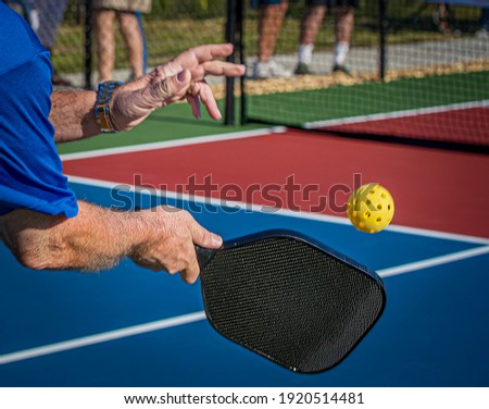 Over the shoulder shot of man hitting a pickleball with a paddle Royalty-Free Stock Photo #1920514481