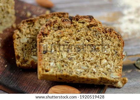 Homemade DIY, organic, healthy bread made of whole rye and wheat flour, hazelnut and seeds: sesame, chia, coriander , laid out on a wooden table.