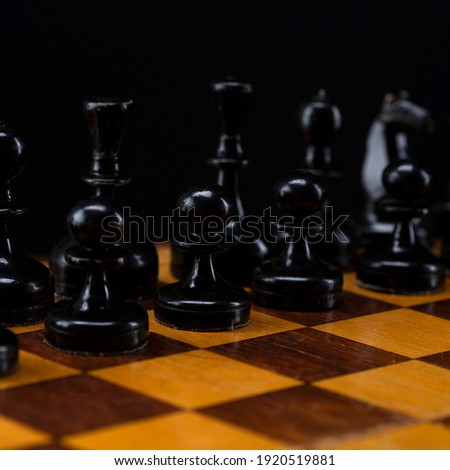 Black chess pieces on a chessboard. An army of black pawns on the table.