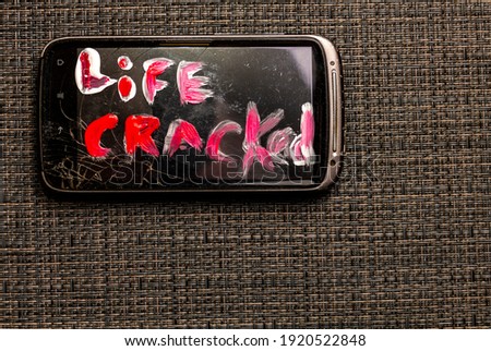 broken smartphone with an inscription on the display - life cracked