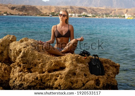 Young woman meditating yoga on the beach on lotus position