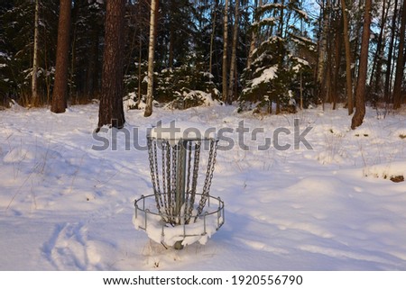 Snowy disc golf basket. Winter picture with plenty of snow. Trees and trunks in the background. Stockholm, Sweden, Europe.