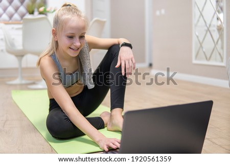 young attractive girl resting after fitness at home and looking at the laptop. quarantine fitness concept.