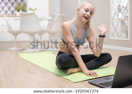 young attractive girl resting after fitness at home and looking at the laptop. quarantine fitness concept.