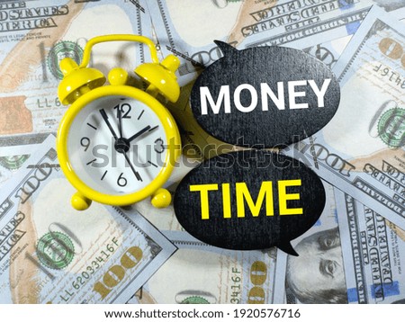 Selective focus.Word MONEY TIME with alarm clock on dollar banknote background.Business concept.