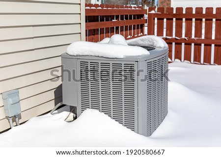 House air conditioning unit covered in snow during winter.. Concept of home air conditioning, hvac, repair, service, winterize and maintenance. Royalty-Free Stock Photo #1920580667