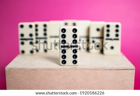 Old fashioned dirty domino on a box with pink solid background
