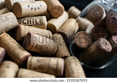 Bunch of wine corks, empty wine bottle and a glass over a black blanket

