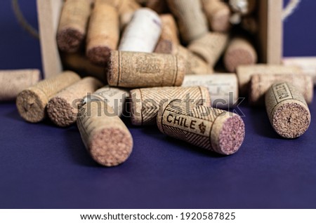 Bunch of wine corks inside a wood box over a purple background
