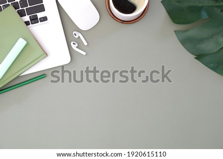 Top view of modern workspace with smart phone, ear phone, laptop and empty notebook on gray table.	