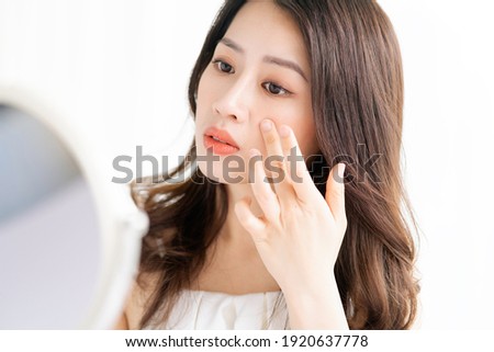 Asian woman sitting makeup in front of mirror