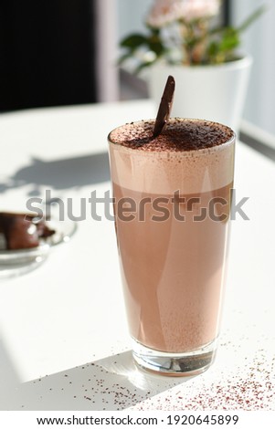 Hot cocoa in a glass with a piece of chocolate 