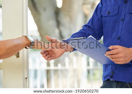 Close-up image of repairman shaking hand of mature client and asking her to sign document