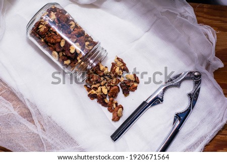 walnut kernels scattered from the jar lie on a napkin next to the nutcracker. High quality photo