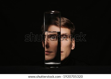 Surreal portrait of a man through the glass of a water can