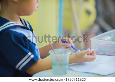 Cute little toddler girl painting with paints color and brush on the wall. Works of child