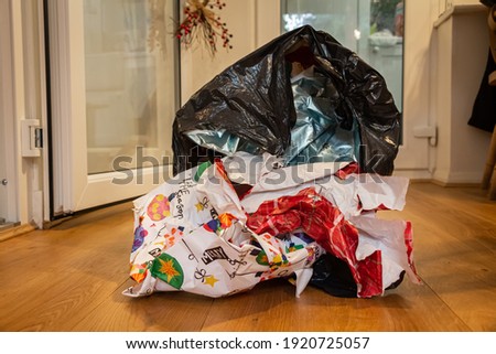 Christmas wrapping paper waste in a bin liner lying on a wooden floor on Christmas day, after presents had been open Royalty-Free Stock Photo #1920725057