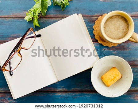 Open book, coffee, sweets, glasses 
 bird's-eye view