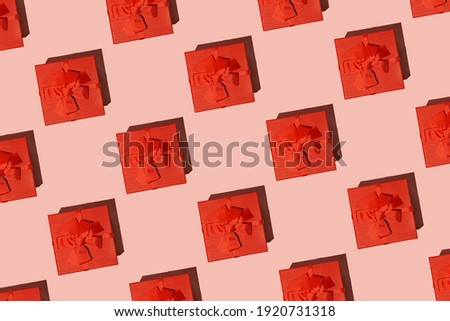 Pattern: red gift boxes on pink background with hard shadows, view from above. Flat lay.