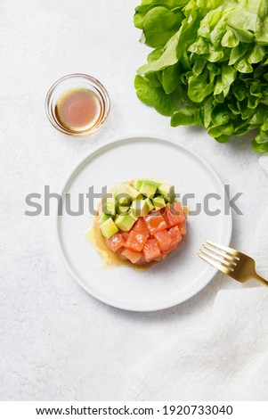 Salmon avocado tartare with sauce on white stone table background