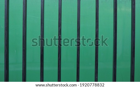 Part of a small black square metal fence with a green metal scene.