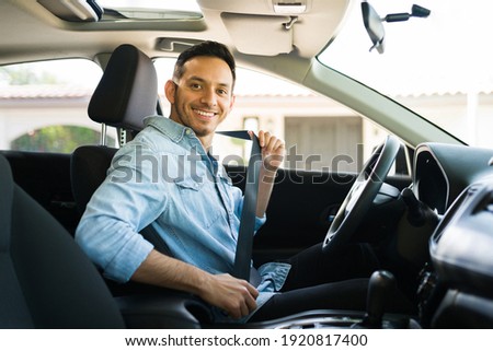 Portrait of an attractive latin man smiling before starting to work as a taxi driver of a car sharing service on a mobile app  Royalty-Free Stock Photo #1920817400