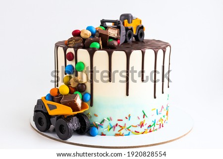 Birthday colorful cake for little boy with toy cars and colorful candies decorations. Holiday, celebration, stylish concept. Construction and transportation theme boys party.